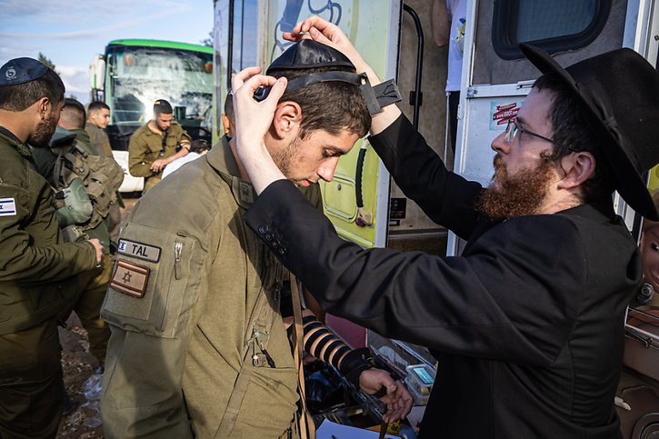 Un groupe de religieux de la communauté Loubavitch fournit aux soldats israéliens des attributs religieux à la frontière avec la bande de Gaza, © KEYSTONE/EPA/CHRISTOPHE PETIT TESSON